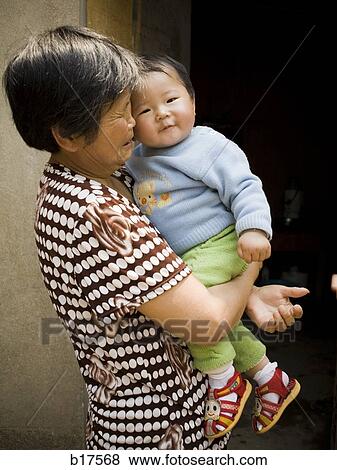 Woman holding baby outdoors View Large Photo Image Stock Photo - Woman holding baby outdoors. Fotosearch