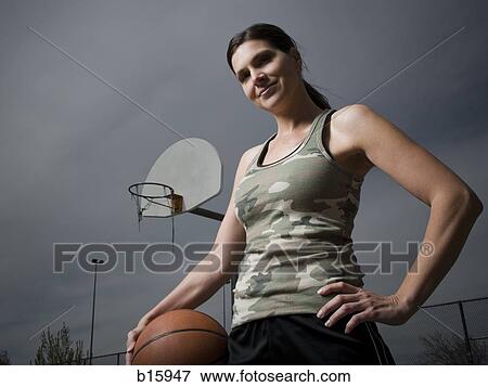Woman holding basketball with net in background View Large Photo Image Stock Photo - Woman holding basketball with net in background. Fotosearch