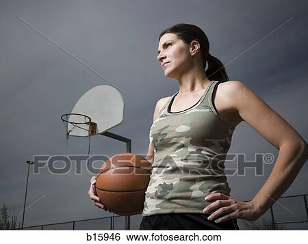 Woman holding basketball with net in background View Large Photo Image Stock Photograph - Woman holding basketball with net in background. Fotosearch