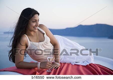 Woman holding champagne flute and reclining outdoors View Large Photo Image Stock Image - Woman holding champagne flute and reclining outdoors. Fotosearch