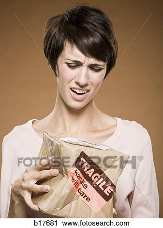 Woman holding crushed cardboard box with fragile label View Large Photo Image Stock Image - Woman holding crushed cardboard box with fragile label. Fotosearch