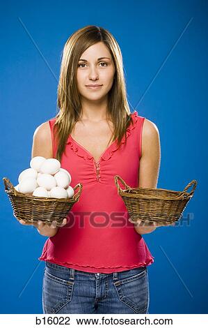 Stock Image - Woman holding empty basket and basket filled with eggs. Fotosearch