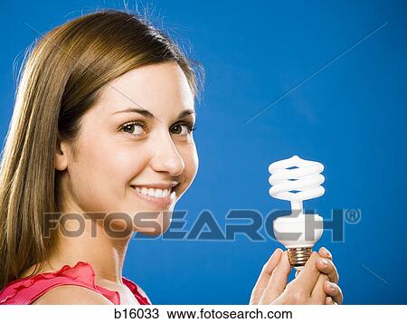 Woman holding energy efficient lightbulb smiling View Large Photo Image Stock Image - Woman holding energy efficient lightbulb smiling. Fotosearch