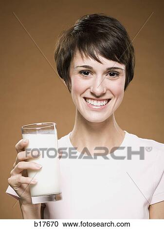 Woman holding glass of milk smiling View Large Photo Image Stock Image - Woman holding glass of milk smiling. Fotosearch