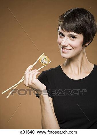 Woman holding sushi with chopsticks smiling View Large Photo Image Stock Image - Woman holding sushi with chopsticks smiling. Fotosearch