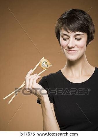 Woman holding sushi with chopsticks smiling View Large Photo Image Stock Photography - Woman holding sushi with chopsticks smiling. Fotosearch