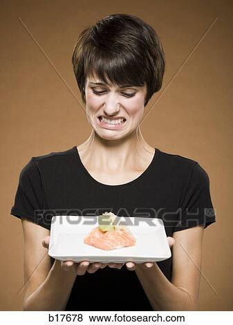 Woman holding sushi with disgusted look View Large Photo Image Stock Photo - Woman holding sushi with disgusted look. Fotosearch