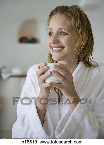 Stock Photo - Woman in bathrobe holding mug smiling. Fotosearch