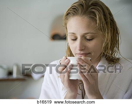 Woman in bathrobe holding mug with eyes closed View Large Photo Image Stock Photo - Woman in bathrobe holding mug with eyes closed. Fotosearch