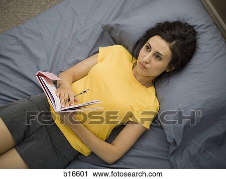 Woman in bed with notebook and pen View Large Photo Image Stock Image - Woman in bed with notebook and pen. Fotosearch