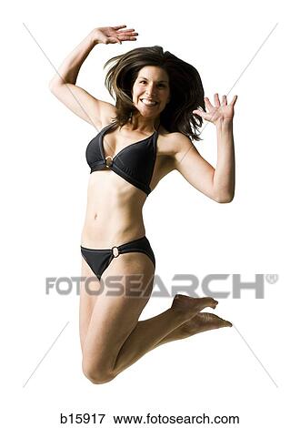 Woman in bikini jumping with hands up smiling View Large Photo Image Stock Photo - Woman in bikini jumping with hands up smiling. Fotosearch