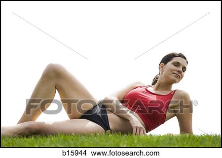 Picture - Woman in bikini lying down in grass. Fotosearch