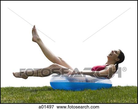 Woman in bikini lying in swimming ring on grass smiling View Large Photo Image Stock Photo - Woman in bikini lying in swimming ring on grass smiling. Fotosearch