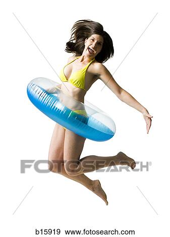 Woman in bikini with swimming ring around waist jumping and smiling View Large Photo Image Stock Photo - Woman in bikini with swimming ring around waist jumping and smiling. Fotosearch
