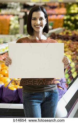 Woman in grocery store holding blank sign View Large Photo Image Picture - Woman in grocery store holding blank sign. Fotosearch