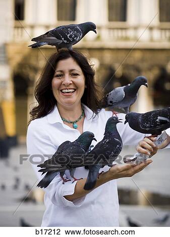 Woman in public square feeding pigeons and smiling View Large Photo Image Stock Image - Woman in public square feeding pigeons and smiling. Fotosearch
