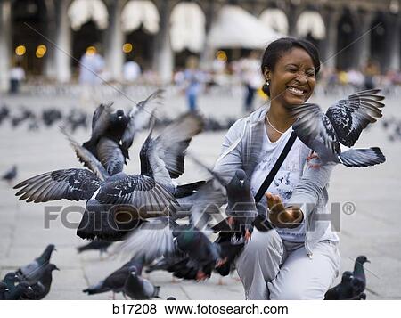Stock Photo - Woman in public square with pigeons squatting. Fotosearch