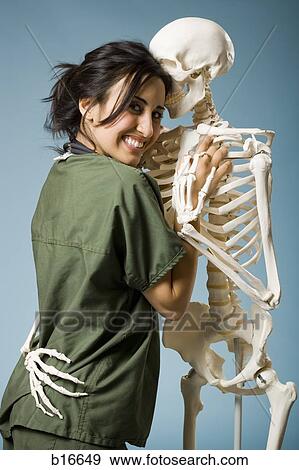 Woman in scrubs dancing with skeleton View Large Photo Image Stock Photo - Woman in scrubs dancing with skeleton. Fotosearch