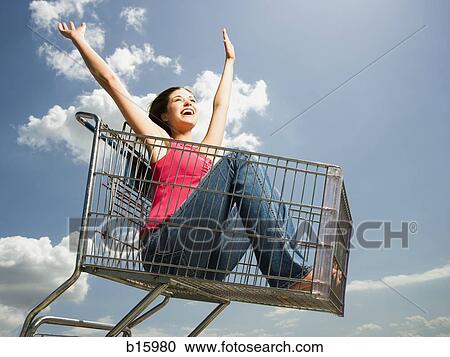 Woman in shopping cart outdoors with arms up smiling View Large Photo Image Stock Image - Woman in shopping cart outdoors with arms up smiling. Fotosearch