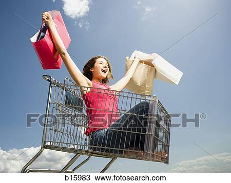 Woman in shopping cart outdoors with shopping bags smiling View Large Photo Image Stock Image - Woman in shopping cart outdoors with shopping bags smiling. Fotosearch