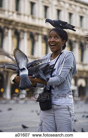 Stock Photo - Woman in square with pigeon on head smiling. Fotosearch