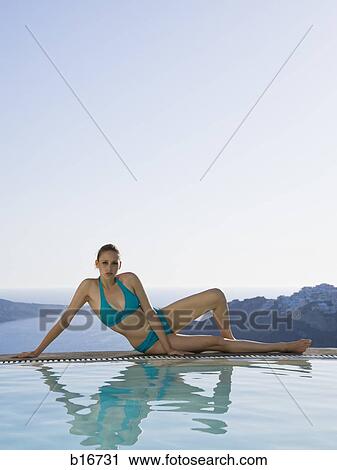 Woman in swimsuit reclining at edge of infinity pool outdoors View Large Photo Image Stock Image - Woman in swimsuit reclining at edge of infinity pool outdoors. Fotosearch