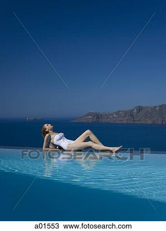 Woman in swimsuit reclining by infinity pool outdoors View Large Photo Image Stock Image - Woman in swimsuit reclining by infinity pool outdoors. Fotosearch