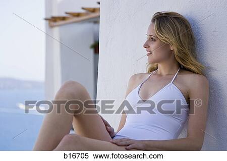 Woman in swimsuit sitting and leaning on wall outdoors smiling View Large Photo Image Stock Photography - Woman in swimsuit sitting and leaning on wall outdoors smiling. Fotosearch
