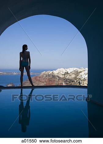 Woman in swimsuit standing at edge of infinity pool rear view View Large Photo Image Stock Image - Woman in swimsuit standing at edge of infinity pool rear view. Fotosearch