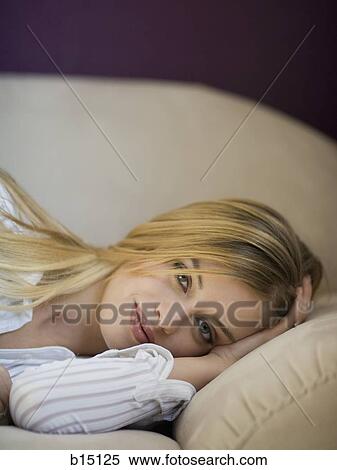 Stock Photography - Woman laying on sofa smiling. Fotosearch