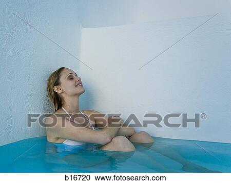 Woman leaning against wall in pool sitting and smiling View Large Photo Image Stock Image - Woman leaning against wall in pool sitting and smiling. Fotosearch