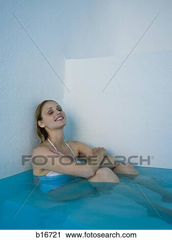 Woman leaning against wall in pool sitting and smiling View Large Photo Image Stock Image - Woman leaning against wall in pool sitting and smiling. Fotosearch