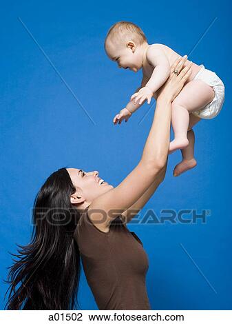 Woman lifting baby in air smiling View Large Photo Image Stock Image - Woman lifting baby in air smiling. Fotosearch