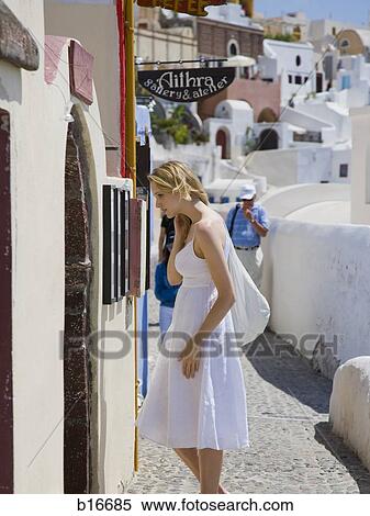 Stock Photography - Woman looking at wall outdoors in village. Fotosearch