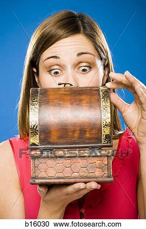 Stock Image - Woman looking in wooden box surprised. Fotosearch