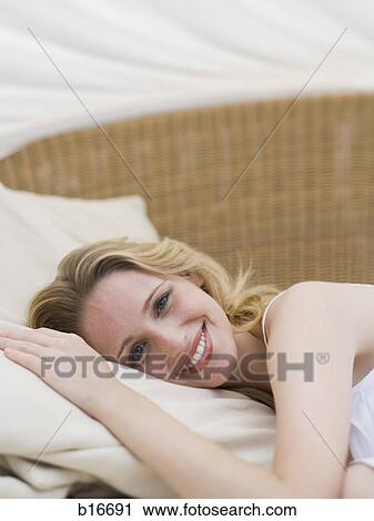 Woman lying down on lounge chair smiling View Large Photo Image Stock Image - Woman lying down on lounge chair smiling. Fotosearch