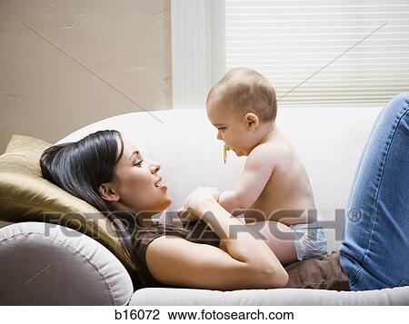 Woman lying down on sofa with baby View Large Photo Image Stock Image - Woman lying down on sofa with baby. Fotosearch