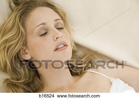 Picture - Woman lying down with eyes closed. Fotosearch