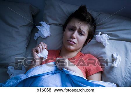 Stock Photo - Woman lying in bed with tissues. Fotosearch