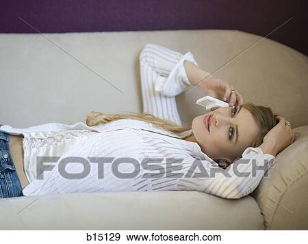 Woman lying on sofa talking on cell phone View Large Photo Image Stock Photo - Woman lying on sofa talking on cell phone. Fotosearch