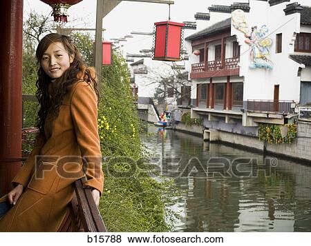 Stock Photo - Woman outdoors by river with Chinese lanterns. Fotosearch