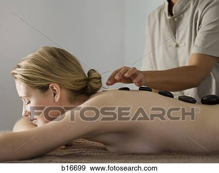Woman placing black stones on woman's spine View Large Photo Image Stock Photo - Woman placing black stones on woman's spine. Fotosearch