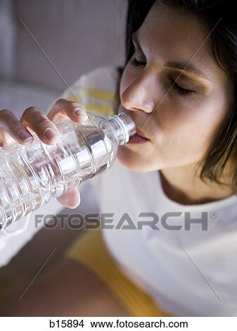 Woman sitting and drinking bottled water View Large Photo Image Picture - Woman sitting and drinking bottled water. Fotosearch