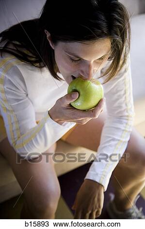 Woman sitting and eating green apple View Large Photo Image Stock Image - Woman sitting and eating green apple. Fotosearch