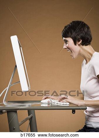 Woman sitting at computer looking excited View Large Photo Image Stock Photography - Woman sitting at computer looking excited. Fotosearch