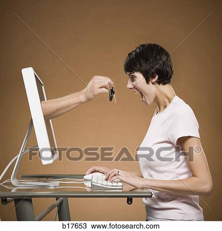 Woman sitting at computer with hand emerging from monitor holding car keys View Large Photo Image Stock Image - Woman sitting at computer with hand emerging from monitor holding car keys. Fotosearch