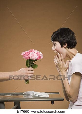 Woman sitting at computer with hand emerging from monitor holding flowers View Large Photo Image Stock Image - Woman sitting at computer with hand emerging from monitor holding flowers. Fotosearch