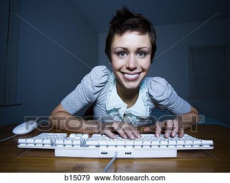 Woman sitting at keyboard typing and smiling View Large Photo Image Stock Photo - Woman sitting at keyboard typing and smiling. Fotosearch
