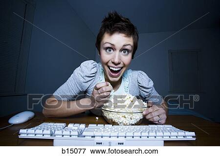Woman sitting at keyboard with bowl of popcorn View Large Photo Image Stock Photo - Woman sitting at keyboard with bowl of popcorn. Fotosearch