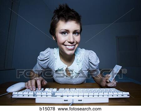 Woman sitting at keyboard with credit card View Large Photo Image Stock Photo - Woman sitting at keyboard with credit card. Fotosearch